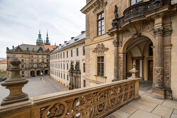 Naklejka premium Ancient stone balcony overlooking the main entrance of a historic building in Prague, adorned with intricate carvings and ornate details, prague, mystique, entrance, ornate