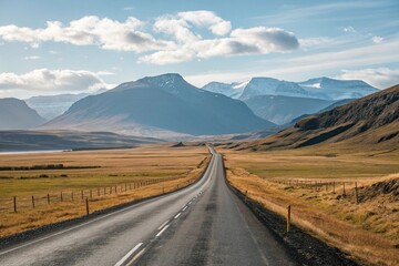 A scenic drive on a straight asphalt road through a vast open landscape with rolling hills and towering mountains visible beyond the horizon, vastness, solitude, asphalt road, blue sky