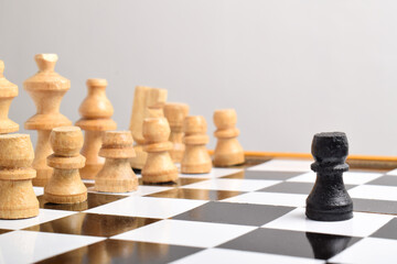 Black chess pawns facing row of white chess pieces.
