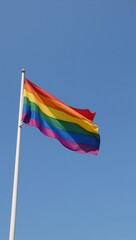 The Gay Pride Flag is depicted waving in a gentle breeze