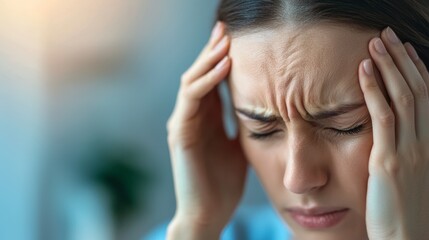 Fototapeta premium A woman is experiencing discomfort, holding her head with a pained expression, suggesting a headache or stress-related issue.