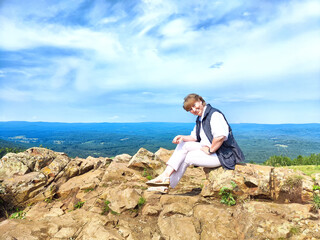 Adventures on a journey. A blogger poses, takes a selfie or podcast in the mountains with a magnificent view