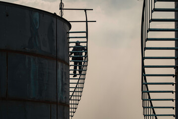 A male walking the upstairs inspection visual record storage tank oil