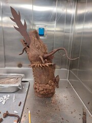 Detailed chocolate dragon sculpture showcased in a professional kitchen. The artistic craftsmanship highlights culinary creativity and fantasy themes, using textured chocolate 