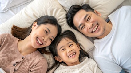 Obraz premium Happy Asian family laying on bed smile, top view