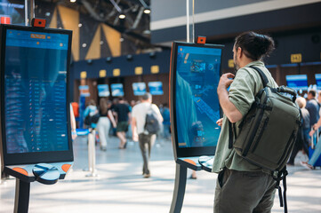 A man checks in for a plane at the electronic check-in desk. A young tourist guy at the airport...