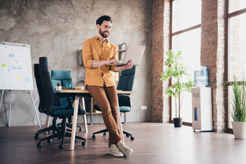 Full length photo of handsome young guy hold netbook dressed yellow shirt formalwear comfortable...