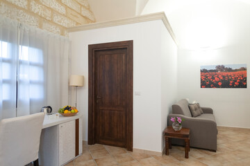 The interior scene showcases a beautifully arranged door, a stylish desk, a comfortable chair, a cozy sofa, and impressive wall art, all contributing to a warm room atmosphere