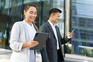 Fototapeta premium Business Professionals Using Digital Devices for Communication Outside Modern Office Building During Afternoon