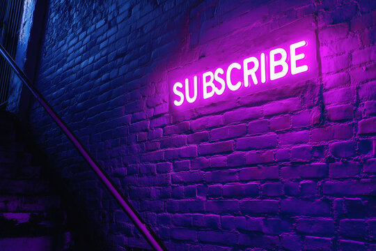 Purple neon with the word "SUBSCRIBE" glowing against a brick wal