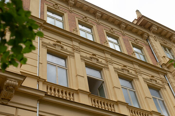 Fototapeta premium This stunning, historically significant building features exquisite architecture, large windows, and charming balconies, set amidst lush greenery that enhances its allure as a notable city landmark