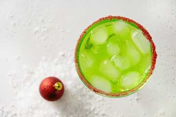 Xmas Green Punch in glass decorated sugar rim on white table make of cool lime sherbet. Tasty drink for Christmas holiday. Rim your festive beverages in red sugar. Close up.