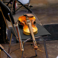 old violin and bow lying on a chair in a theater