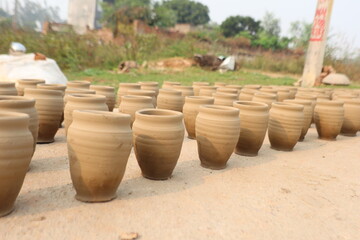 Freshly crafted raw clay pots drying under sunlight, showcasing traditional pottery techniques and natural craftsmanship in a rural settings, whole process to make pottery, selective focus 