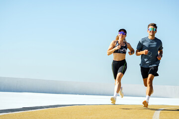 Two Athletes Running on a Bright Outdoor Track During a Sunny Morning Workout Session