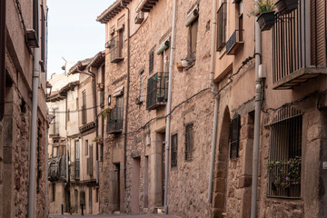 Obraz premium Narrow cobblestone street with rustic stone buildings and balconies in a charming historic Spanish village