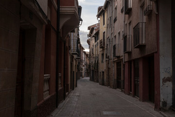 Narrow and quiet cobblestone street lined with traditional buildings in a historic European village at dusk © larrui