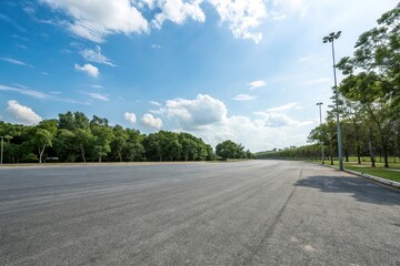 Empty asphalt road stretches into the horizon as a bright blue sky meets lush green trees in the background, calm, freedom, empty road