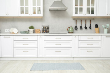 Stylish soft rug on wooden floor in kitchen