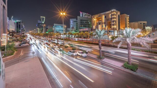 Cityscape aerial night timelapse of Riyadh, Saudi Arabia, featuring illuminated famous towers, skyscrapers, King Fahd Road and busy traffic. Palms and streetlights line the main highway through a city