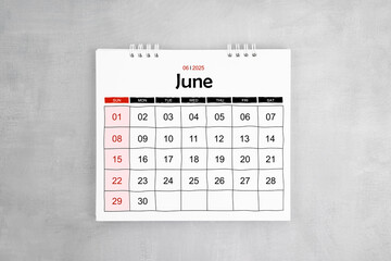 June 2025 desk calendar on gray cement wall background.