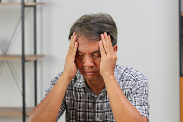 Asian senior man is having a headache.