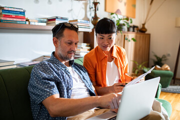 Happy couple doing financials at home with laptop