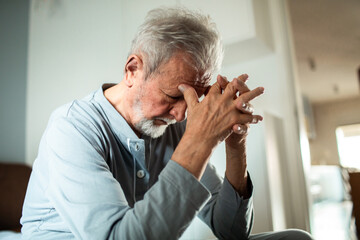Elderly man deep in thought sitting at home