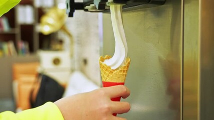 Close-up ice cream street vendor filling an ice cream cone by machine, slow motion video