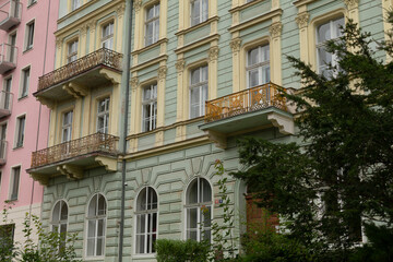 Fototapeta premium This stunning facade features a classical design with elegant balconies covered in lush greenery, perfect for attracting attention in real estate and captivating architectural visuals