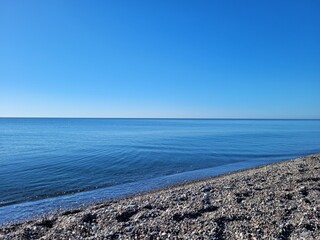 SEA -  endless blue sea, bright water surface, pebble beach, sunny day, calm, round gray stones