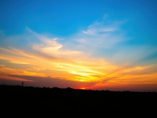 Obraz premium A beautiful sunset scene with a clear blue sky and vibrant orange hues, serene atmosphere, sunset colors, natural beauty