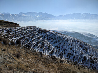 Winter view of landcape. Snow-capped mountains in the clouds  and haze against a blue sky. Vivid...