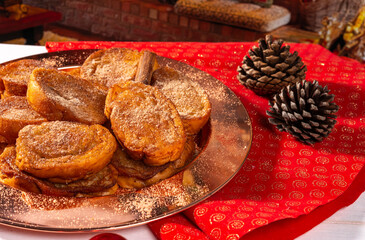 Traditional brazilian christmas Rabanadas with egg yolk crea and cinnamon, Spanish Torrijas on golden plate on a christmas dinner table.