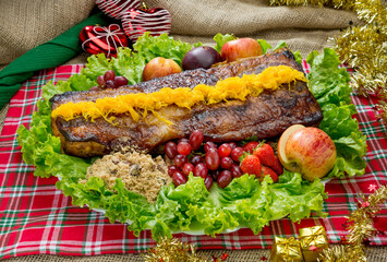 Roasted pork belly, with egg Threads, bacon crumbs with raisins, lettuce and fresh fruits on a Christmas dinner table