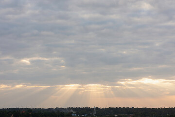 sky filled with clouds during either sunrise or sunset. Sunlight is breaking through the clouds in several places, creating a dramatic effect known as “God rays” or “crepuscular rays.”