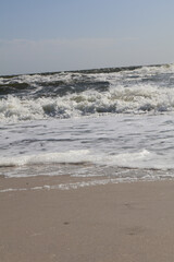 Gentle foamy waves washing over the sandy beach of the Black Sea on a bright sunny day, creating a tranquil seascape