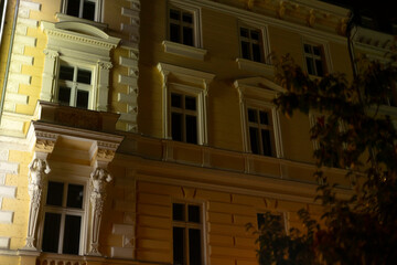 A stunning historic building facade is beautifully illuminated at night, highlighting its intricate architectural details and adorned with warm, inviting tones that create an enchanting atmosphere