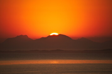 Sunset on the beach in Rio de Janeiro with the sea and mountains in the background. Postcard image