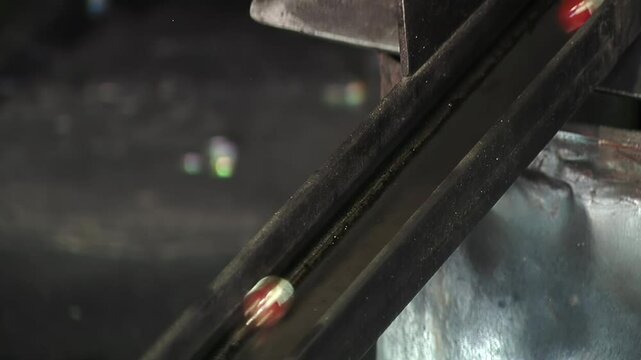 Molten Marbles on a Metal Slide in a Manufacturing Process, Molten Glass Marbles Rolling Down a Metallic Conveyor - Close Up - 4K