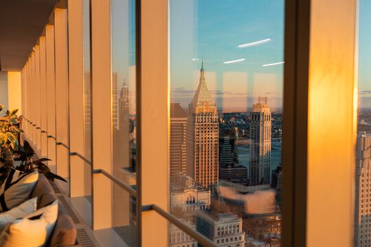 view of downtown manhattan from conference room of skyscraper at golden hour