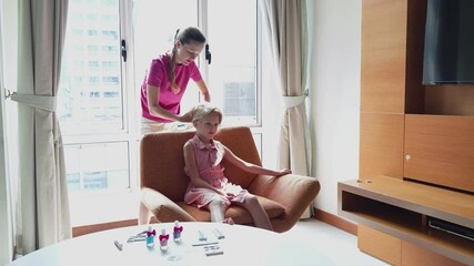 A joyful mother and daughter together engages in nail art 
