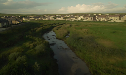 Naklejka premium Serene aerial view of a tranquil river meandering through a residential area, showcasing a harmonious blend of nature and modern housing.