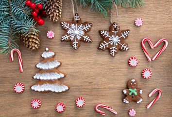 Christmas tree with christmas gingerbread, candy, red berries and cones spruce on a wooden background with space for text. Top view, flat lay