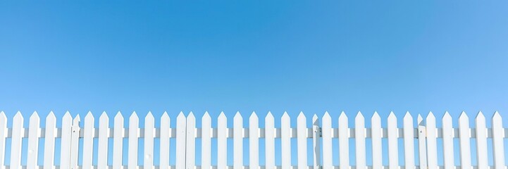 Fototapeta premium Large blue sky reflecting off a calm and clean white picket fence, blue sky, serene landscape