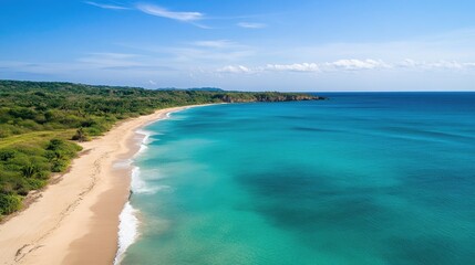 Obraz premium Aerial view of a beautiful tropical landscape with a serene sandy beach and tranquil blue ocean waters under a clear sky.