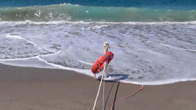 Rope with a stake and life buoy that delimit the part of the beach given in concession to a beach resort.