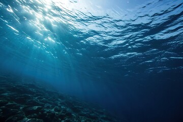 Obraz premium Dark blue ocean surface viewed from an angle with sunlight filtering down through the water, sunlight filter, ocean surface from below