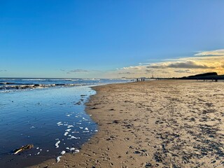 Serene Sandy Beach at Low Tide with Gentle Waves and a Golden Horizon