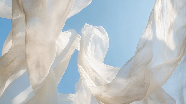 Light white fabric sways gracefully in the wind, beautifully contrasting with the serene backdrop of a bright blue sky.
